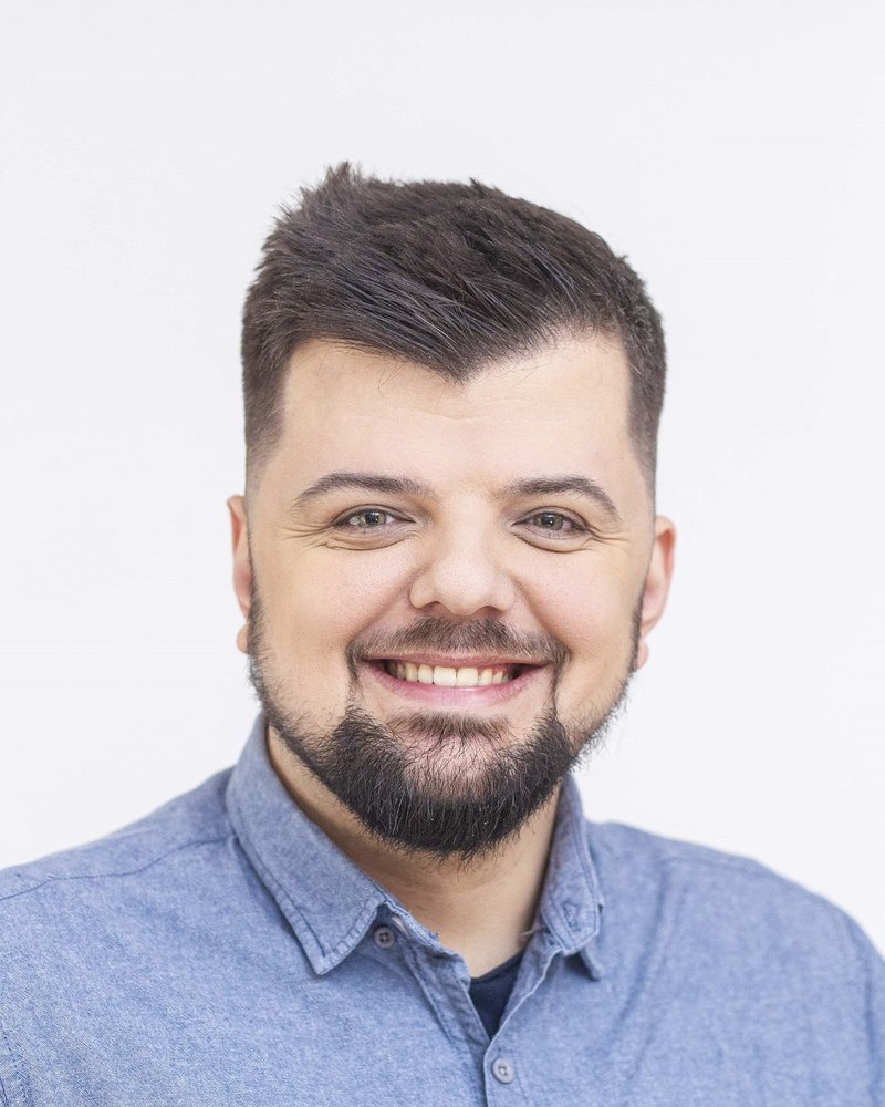 Kacper Sieradziński, uśmiechnięty, w niebieskiej koszuli